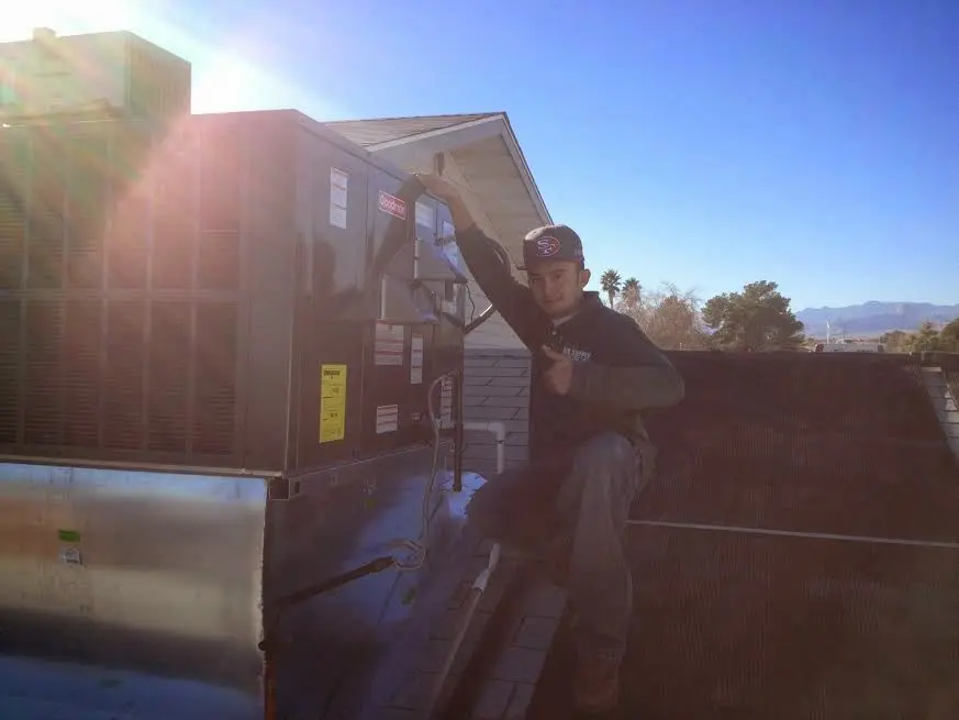 HVAC technician performing AC Tune-Up on a rooftop unit in Westwood